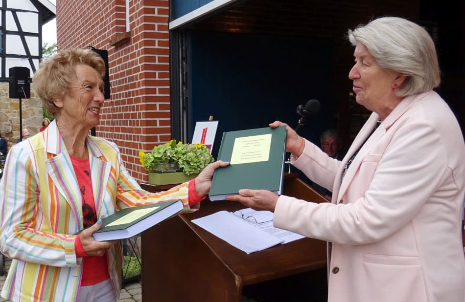 Ursula Kampmann (links) erhält den Ausdruck ihrer Datei des Ortfamilienbuch Glane.